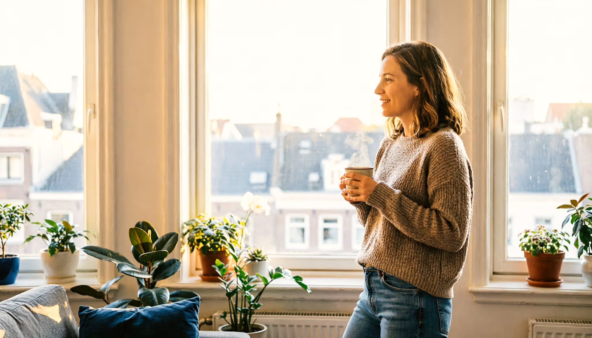 Een vrouw geniet van een rustig moment thuis met een kop koffie in het ochtendlicht.