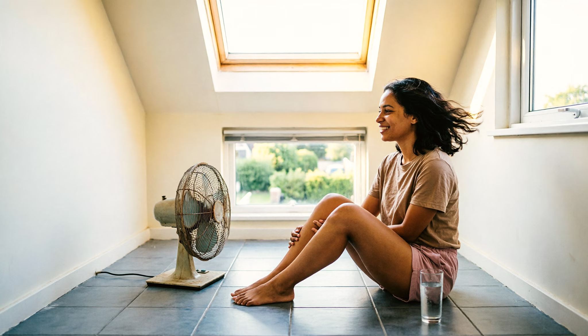 Income from other activities explained: a young woman cooling off in front of a floor fan in a Dutch top-floor room on an overcast summer afternoon