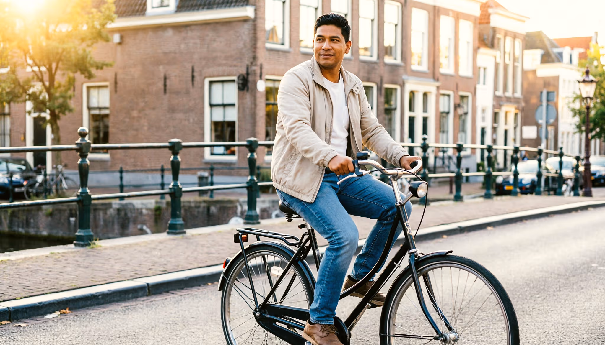 Een man fietst in de late middag over een rustige brug in een Nederlandse stad
