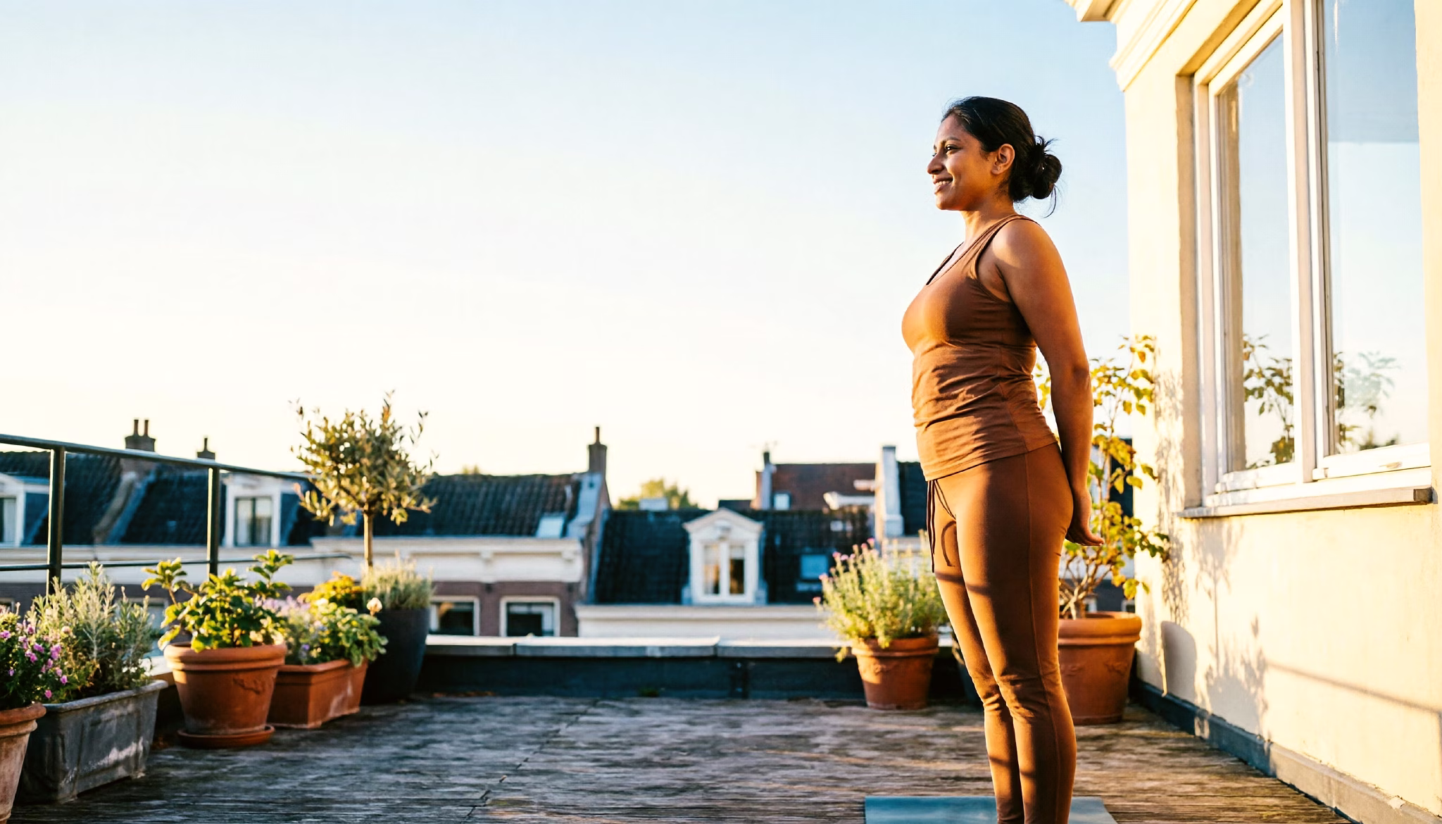 Een jonge professional die een rustige ochtend-yogahouding doet op een zonnig Amsterdams dakterras.