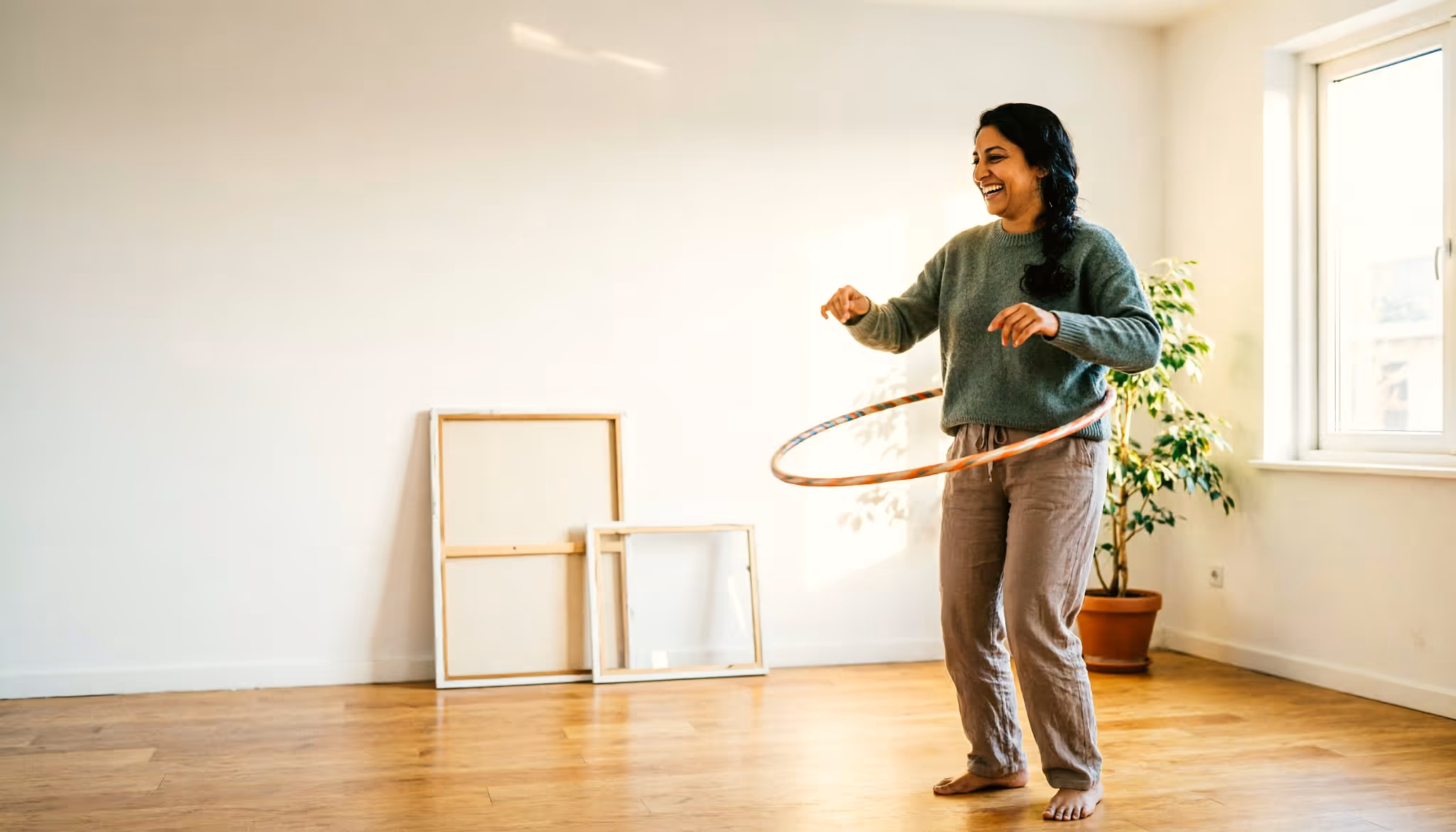 Een jonge vrouw speelt met een hoelahoep in een zonnige Nederlandse woonkamer