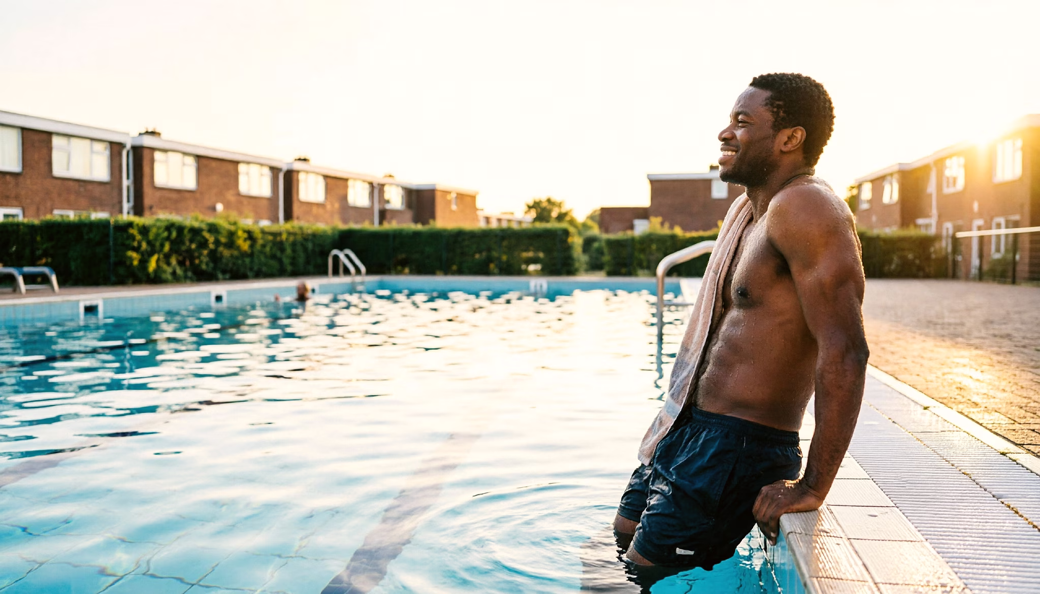 A man relaxing at the edge of an open-air neighbourhood swimming pool in the Netherlands after an evening swim