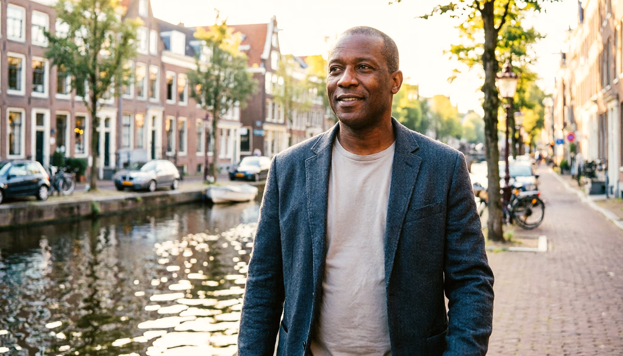 A man in his late forties walks along an Amsterdam canal in the morning light