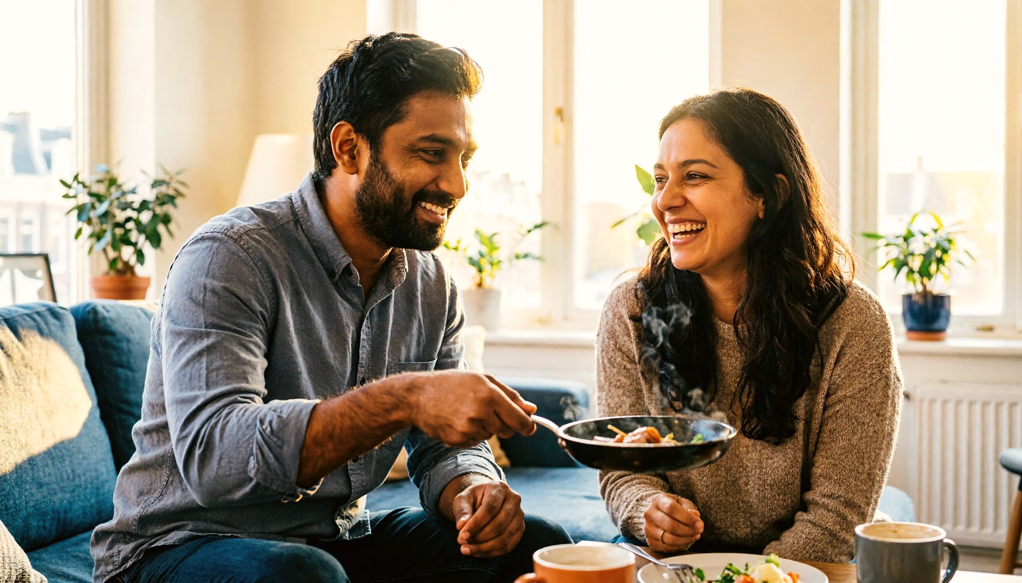A couple enjoy a cosy gourmetten evening at home, mini pans sizzling between them